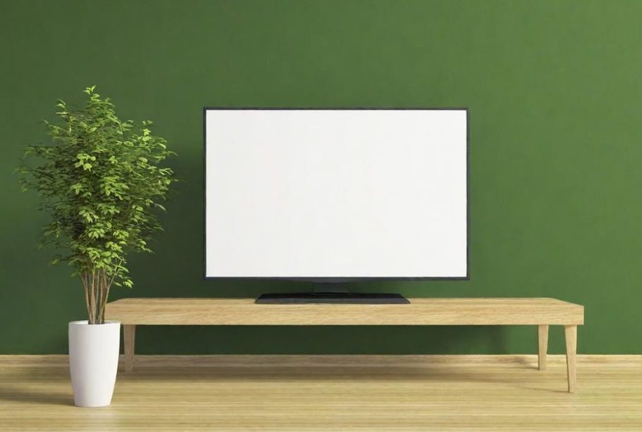 Symbolbild für Fernsehauftritte Moderne Wohnzimmerszene mit Fernseher auf einem Holzregal vor grünem Wandhintergrund.
