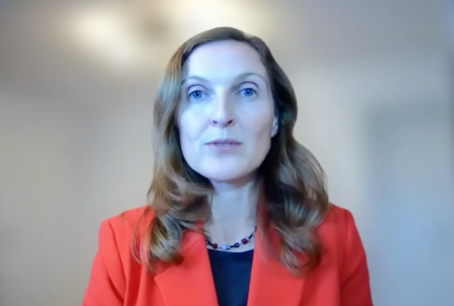 Szene aus Auslandsjournal Doku Frau mit rotem Jacket vor verwischtem Hintergrund bei einer Fernsehaufnahme